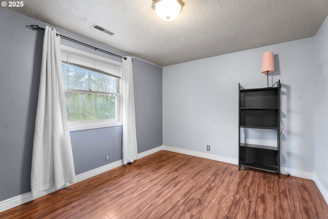 spare room with a textured ceiling and wood-type flooring