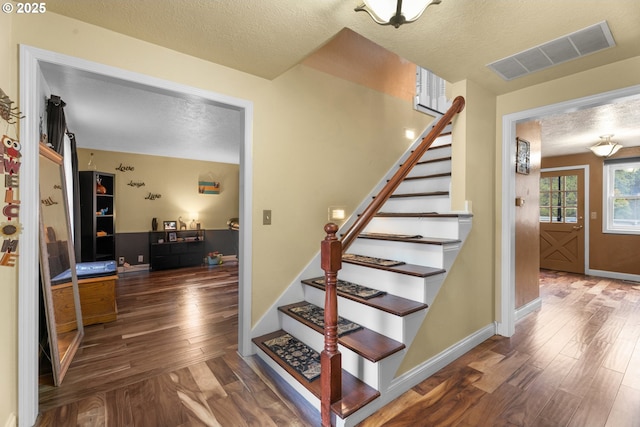 staircase featuring a textured ceiling and hardwood / wood-style flooring