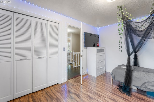 bedroom with a closet, hardwood / wood-style floors, and a textured ceiling