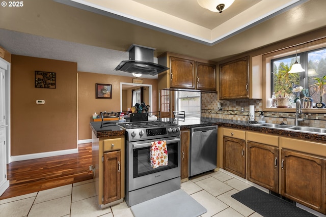 kitchen featuring appliances with stainless steel finishes, kitchen peninsula, light tile patterned floors, sink, and wall chimney range hood