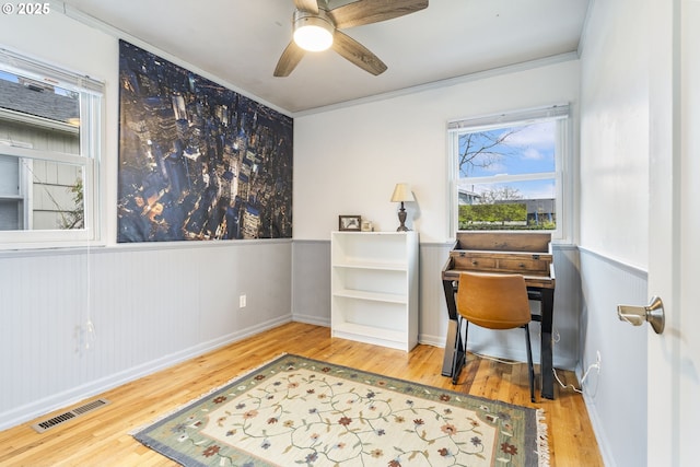 office with ceiling fan, ornamental molding, wood finished floors, and visible vents