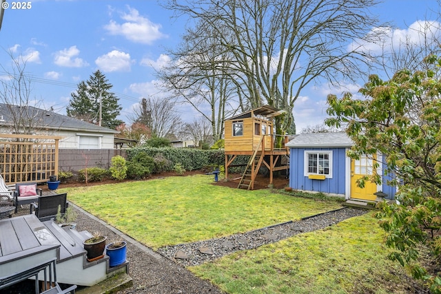 view of yard featuring a fenced backyard, a playground, and an outdoor structure