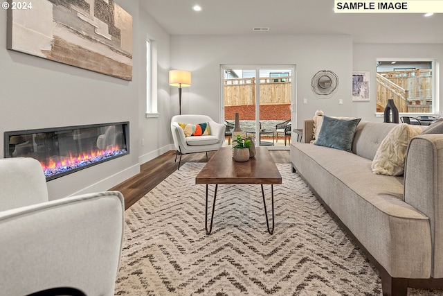 living room featuring baseboards, visible vents, a glass covered fireplace, wood finished floors, and recessed lighting