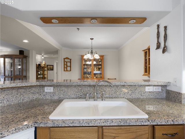 kitchen with sink, ornamental molding, a notable chandelier, and pendant lighting