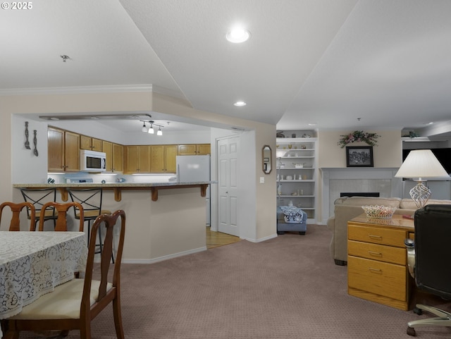 interior space featuring crown molding, a fireplace, built in shelves, light colored carpet, and a breakfast bar