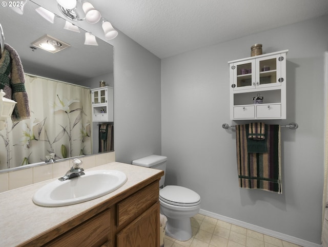 bathroom featuring a textured ceiling, toilet, and vanity