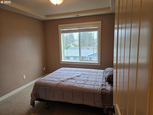 carpeted bedroom featuring visible vents, baseboards, and a tray ceiling