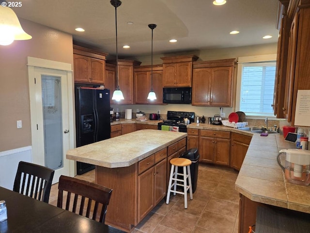 kitchen with a kitchen island, recessed lighting, a sink, black appliances, and a kitchen breakfast bar