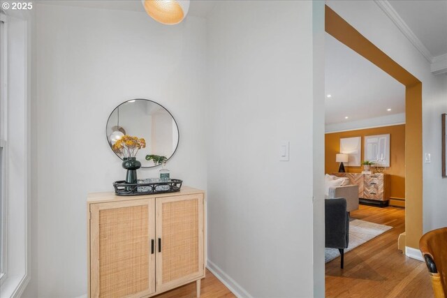 hallway with light wood-type flooring, ornamental molding, recessed lighting, a baseboard radiator, and baseboards