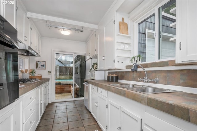 kitchen with dark tile patterned flooring, a sink, white cabinetry, appliances with stainless steel finishes, and decorative backsplash