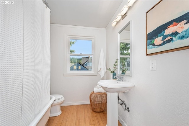 bathroom featuring shower / bath combination with curtain, toilet, baseboards, and wood finished floors