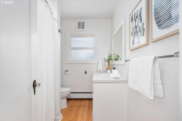 full bathroom featuring vanity, a shower with curtain, wood finished floors, toilet, and baseboard heating