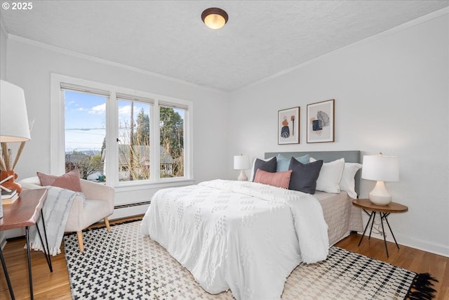 bedroom featuring a textured ceiling, crown molding, baseboards, and wood finished floors