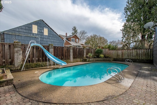 view of swimming pool featuring a fenced in pool, a water slide, a fenced backyard, and a patio area