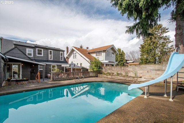 view of pool featuring a fenced in pool, a water slide, and a wooden deck