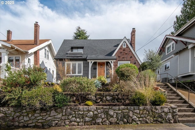 tudor-style house featuring stairs and roof with shingles