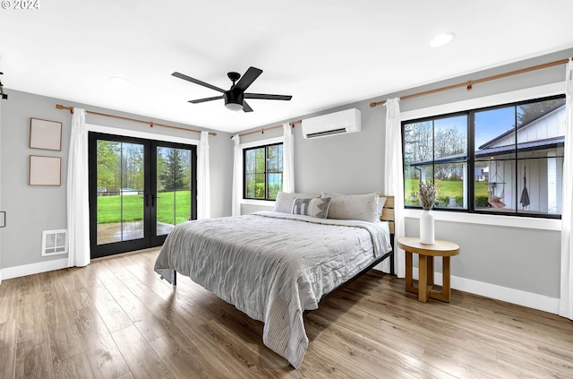 bedroom featuring light wood finished floors, visible vents, access to outside, french doors, and a wall mounted AC