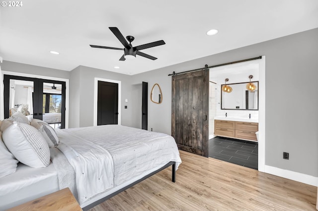 bedroom featuring french doors, a barn door, dark wood-style flooring, and recessed lighting