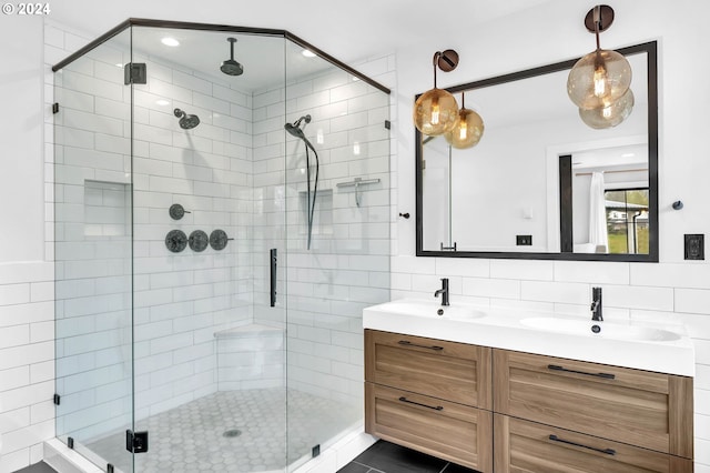 bathroom featuring double vanity, a shower stall, backsplash, and a sink