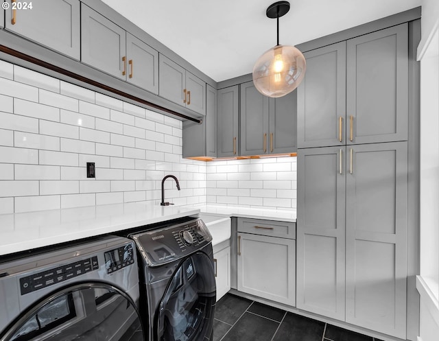 laundry area with cabinet space, a sink, dark tile patterned floors, and separate washer and dryer