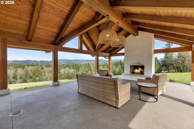 view of patio / terrace with a large fireplace, a wooded view, and a gazebo