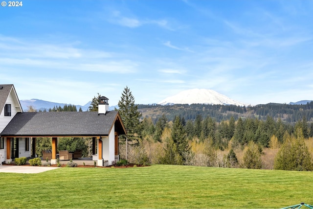 view of yard featuring a forest view and a mountain view