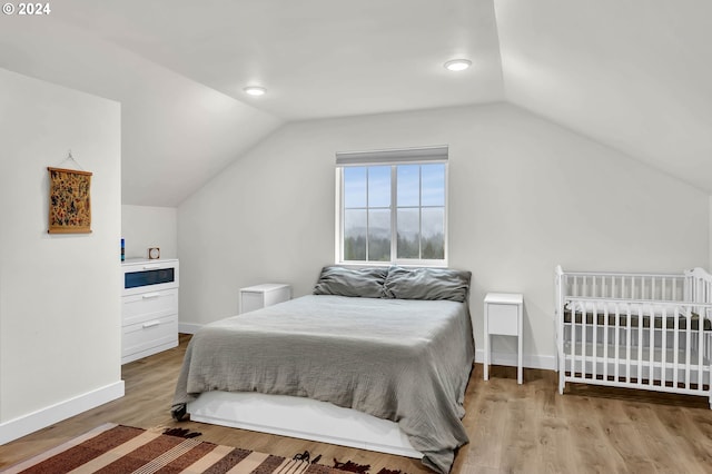 bedroom with lofted ceiling, baseboards, and wood finished floors