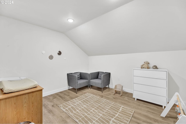 living area with light wood-style flooring, baseboards, and vaulted ceiling