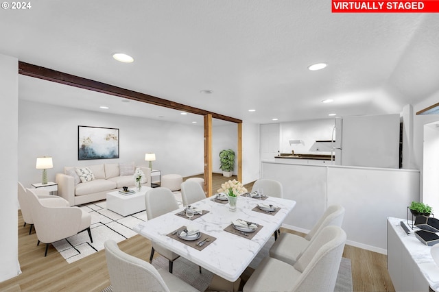 dining space featuring light wood finished floors, beamed ceiling, and recessed lighting