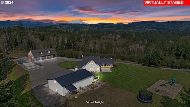 aerial view at dusk with a mountain view and a view of trees