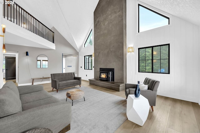 living area featuring a large fireplace, high vaulted ceiling, plenty of natural light, and wood finished floors