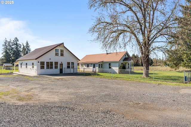 modern inspired farmhouse with metal roof, a front lawn, and fence