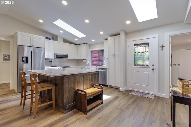 9403 SW 74th Ave, Portland, OR 97223 - kitchen with a skylight, appliances with stainless steel finishes, vaulted ceiling, white cabinetry, and a center island