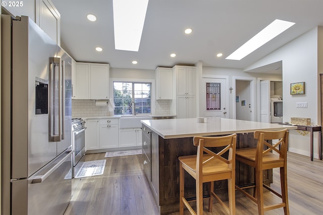 9403 SW 74th Ave, Portland, OR 97223 - kitchen with appliances with stainless steel finishes, a skylight, washer / dryer, light wood-type flooring, and light countertops