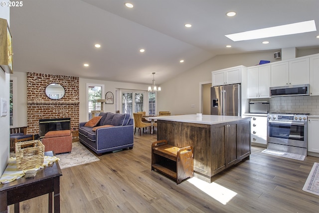 9403 SW 74th Ave, Portland, OR 97223 - kitchen featuring appliances with stainless steel finishes, lofted ceiling, white cabinets, wood finished floors, and tasteful backsplash