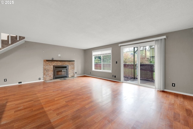 unfurnished living room featuring a stone fireplace, a textured ceiling, and light hardwood / wood-style flooring