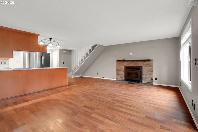 unfurnished living room featuring a stone fireplace and light hardwood / wood-style floors