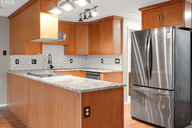 kitchen featuring pendant lighting, stainless steel fridge, light stone counters, and tasteful backsplash