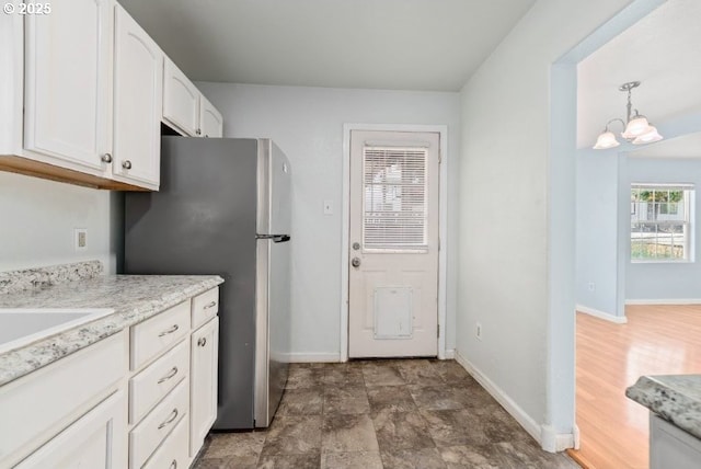 1235 SE Booth Ave, Roseburg, OR 97470 - kitchen featuring a chandelier, freestanding refrigerator, white cabinetry, and baseboards