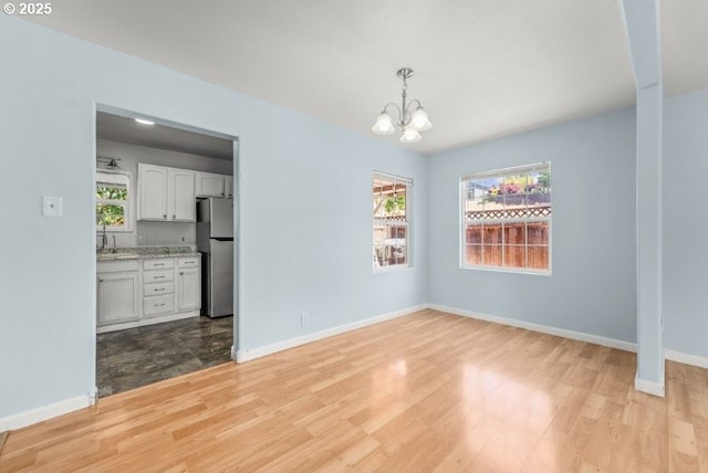 1235 SE Booth Ave, Roseburg, OR 97470 - spare room featuring a chandelier, light wood-type flooring, baseboards, and plenty of natural light