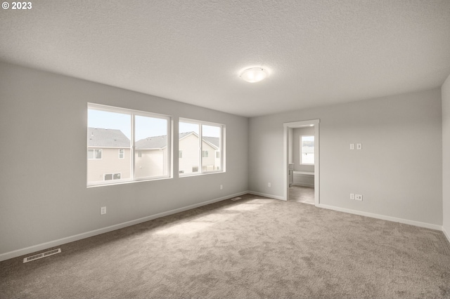 carpeted spare room with a textured ceiling