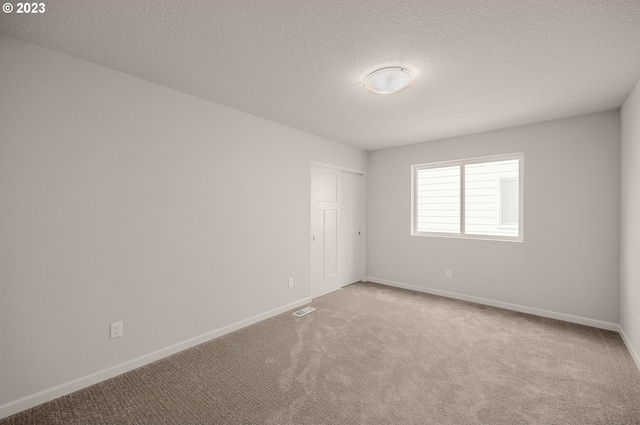 carpeted empty room featuring a textured ceiling