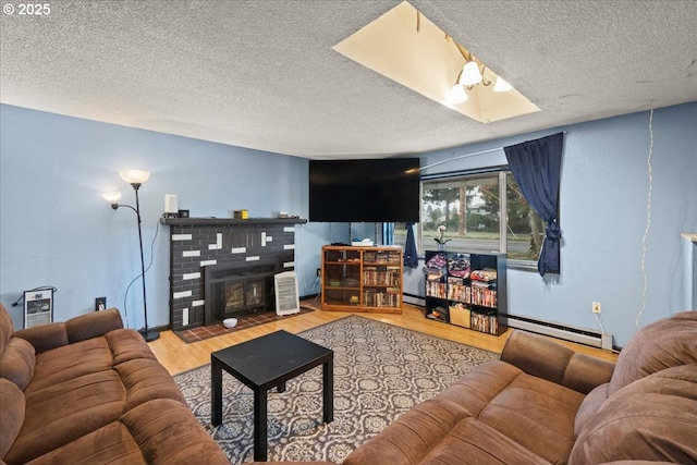 living room with a textured ceiling, baseboard heating, hardwood / wood-style floors, and a brick fireplace