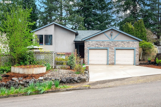 tri-level home featuring concrete driveway, stone siding, a shingled roof, fence, and a garage