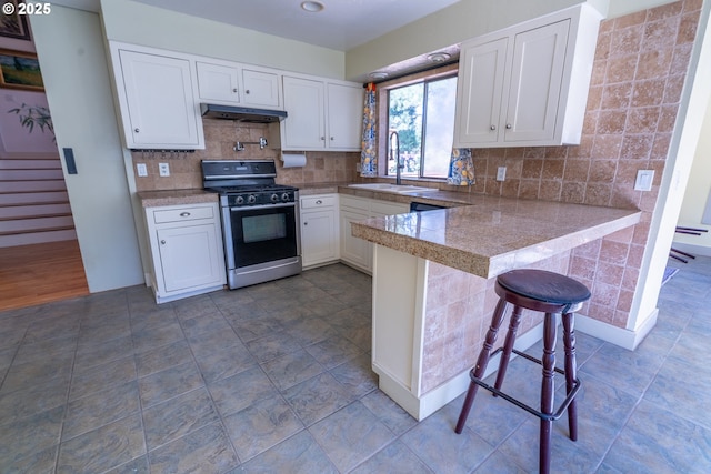 kitchen featuring a sink, gas range, tile countertops, and white cabinetry