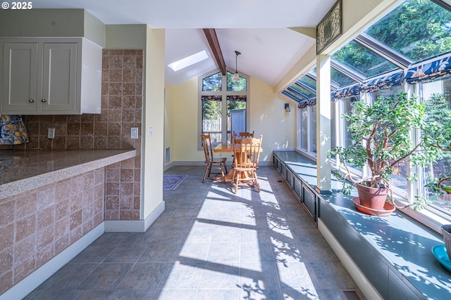sunroom with lofted ceiling with skylight and baseboards