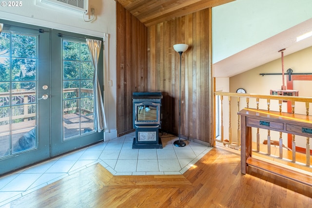 interior space with a wood stove, a wall mounted air conditioner, wood walls, wood ceiling, and french doors