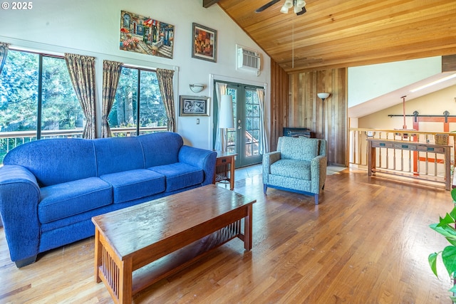 living area with beamed ceiling, a wall mounted AC, high vaulted ceiling, a ceiling fan, and wood finished floors