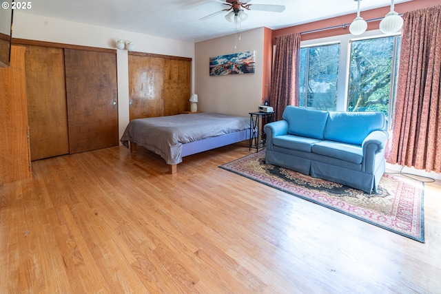 bedroom with ceiling fan, multiple closets, and light wood finished floors