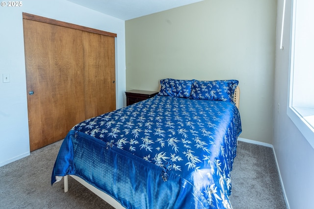 carpeted bedroom featuring baseboards and a closet